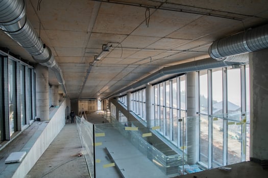 A captivating view of a modern business building under construction, showcasing its raw industrial interior with exposed steel beams and concrete walls bathed in the warm, golden hues of a sunset photo