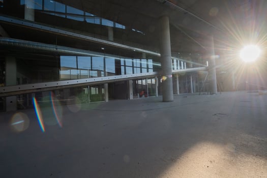 A captivating view of a modern business building under construction, showcasing its raw industrial interior with exposed steel beams and concrete walls bathed in the warm, golden hues of a sunset photo