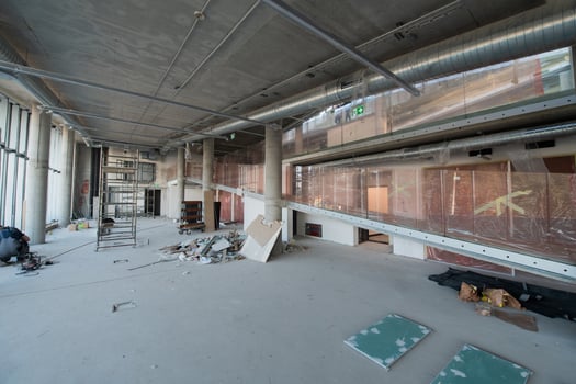 A captivating view of a modern business building under construction, showcasing its raw industrial interior with exposed steel beams and concrete walls bathed in the warm, golden hues of a sunset photo