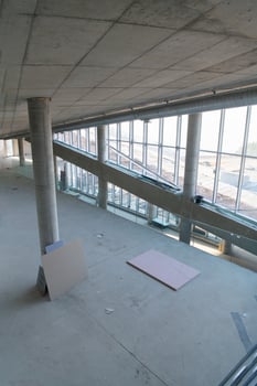 A captivating view of a modern business building under construction, showcasing its raw industrial interior with exposed steel beams and concrete walls bathed in the warm, golden hues of a sunset photo