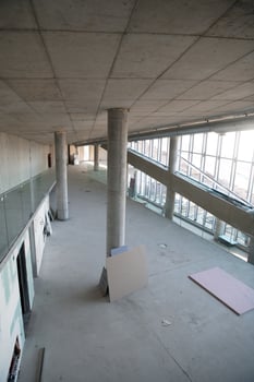 A captivating view of a modern business building under construction, showcasing its raw industrial interior with exposed steel beams and concrete walls bathed in the warm, golden hues of a sunset photo