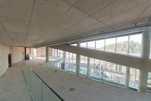 A captivating view of a modern business building under construction, showcasing its raw industrial interior with exposed steel beams and concrete walls bathed in the warm, golden hues of a sunset photo