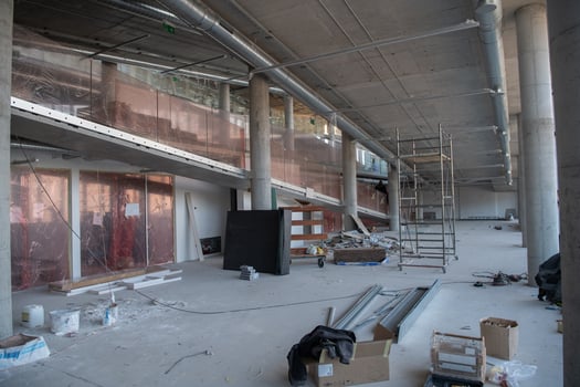 A captivating view of a modern business building under construction, showcasing its raw industrial interior with exposed steel beams and concrete walls bathed in the warm, golden hues of a sunset photo