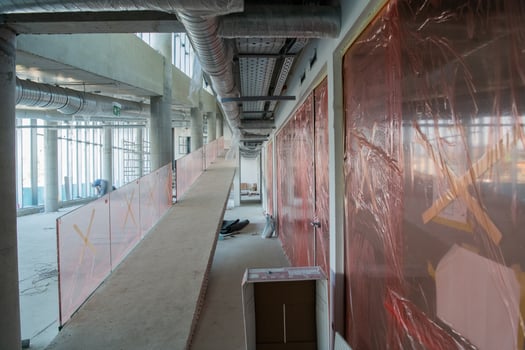 A captivating view of a modern business building under construction, showcasing its raw industrial interior with exposed steel beams and concrete walls bathed in the warm, golden hues of a sunset photo