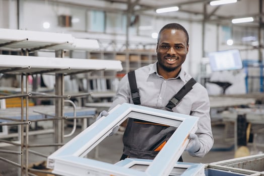 Factory worker holding aluminum window frame, smiling at camera photo