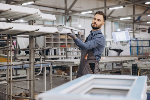 Factory worker storing aluminum window frames in warehouse photo