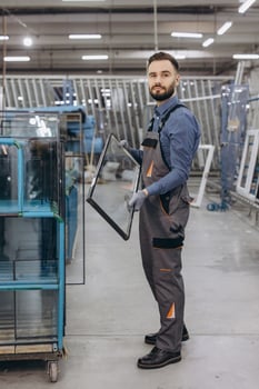 Factory worker holding glass pane for pvc windows and doors production photo