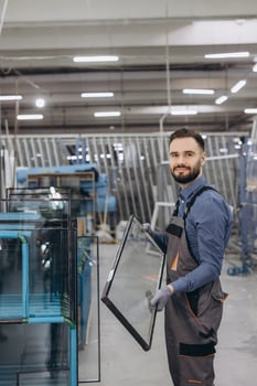 Factory worker carrying glass window pane in production line photo