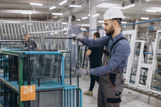 Factory worker handling glass pane for pvc windows production photo