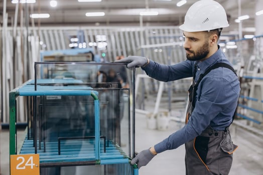 Factory worker handling glass pane for PVC windows and doors production photo