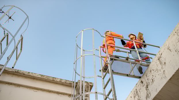Two maintenance technicians and solar panel installers are planning to install solar cells on the roof of a building. photo
