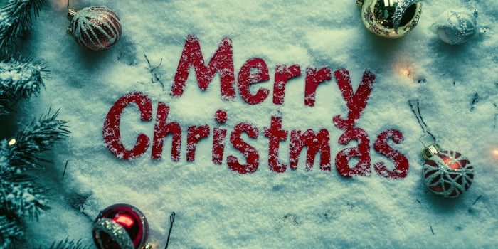 The word Merry Christmas written in red on white snow, with Christmas decorations around it. photo