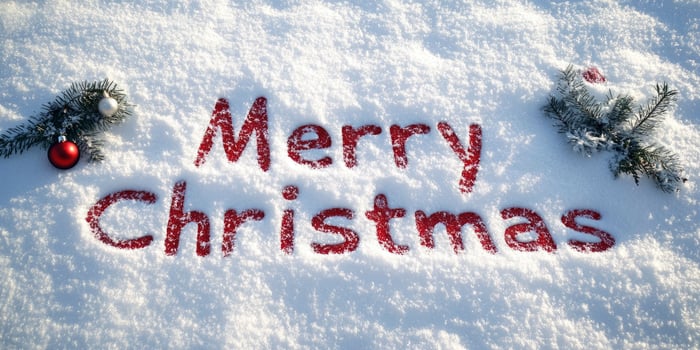 The word Merry Christmas written in red on white snow, with Christmas decorations around it. photo