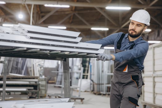 Factory worker moving aluminum profiles for windows and doors production photo