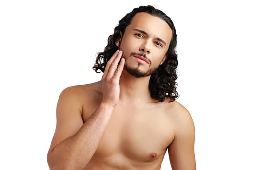 Young man with curly hair thoughtfully posing against a plain background photo