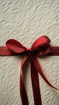 Gift wrapped in brown paper with a red ribbon on a dark surface photo