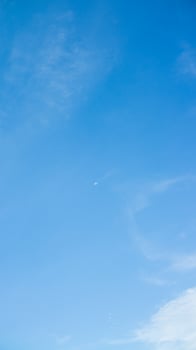 A man flying a kite in a blue sky photo