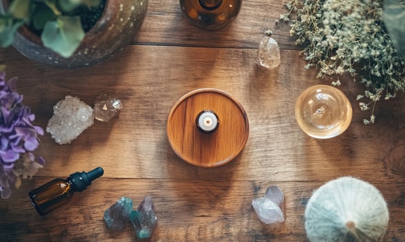 A bottle of essential oil is on a wooden table with other bottles and crystals photo