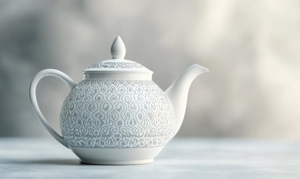 A white tea pot with a black design sits on a table photo