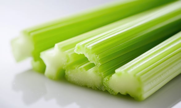 A bunch of celery sticks are on a white plate photo