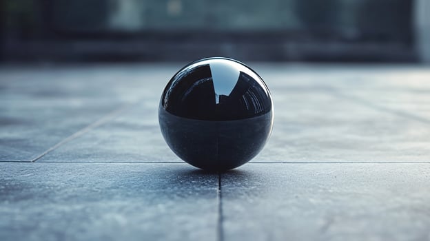 A black ball is sitting on a grey floor photo