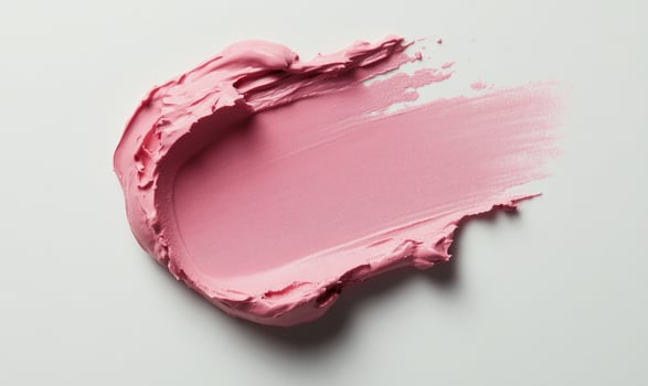A pink blob of makeup is smeared on a white background photo