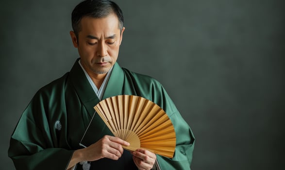 an asian man in a kimono holding a fan photo