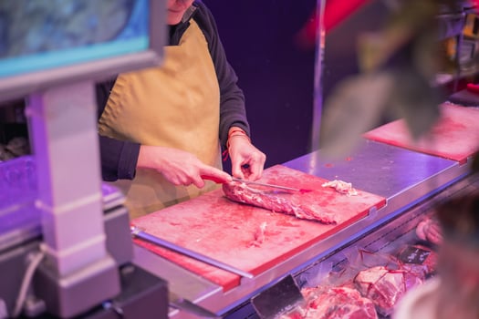 Closeup of Female Butcher Cutting Lamb Meat in Butcher Shop photo