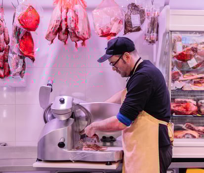 Skilled Butcher Operating Meat Cutting Machine photo