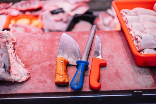 closeup Two Butcher Knives and Knife Sharpener on Meat Cutting Board in Butcher Shop photo