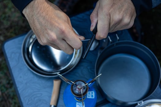 Top-Down View of Hands Lighting Camping Stove with Flint photo