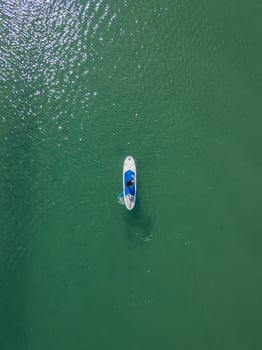 vertical cenital view Young woman paddling with her blue paddleboard on the sea photo