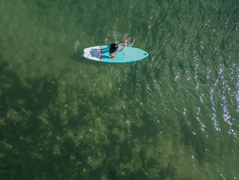 cenital copyspace above view Young Latin paddleboarding with board in the sea on a sunny summer day photo