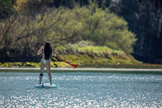 copyspace Latin girl Paddleboarding Away on River photo