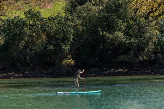 Multicultural Woman in bikini Paddleboarding on River side view photo