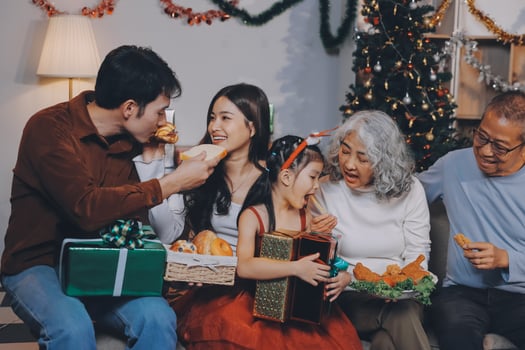 Portrait of Asian family exchanging presents during christmas at home. Attractive happy people holding gift box, celebrate holiday thanksgiving, xmas eve tradition in living room in house together. photo