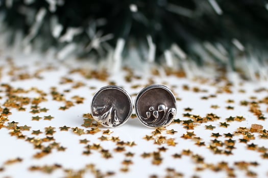 Handmade round silver earrings with nature-inspired design on white sparkly Christmas background. photo