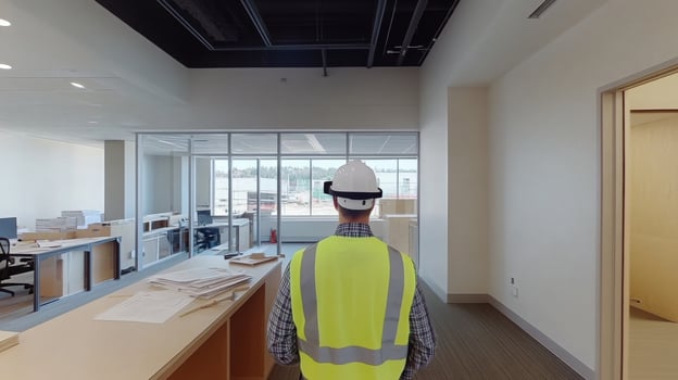 A construction management expert stands in a newly developed office, equipped with a hard hat and safety vest. He interacts with AI tools while surveying the workspace and planning for completion. photo