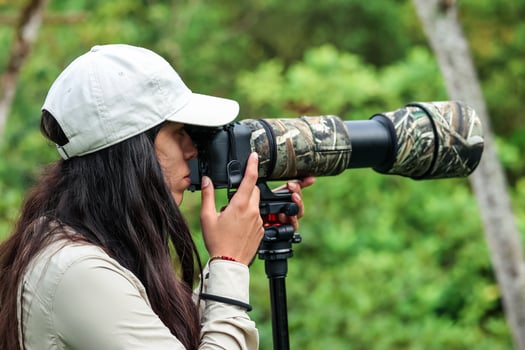 Latin woman nature photographer capturing wildlife with telephoto lens in the jungle photo