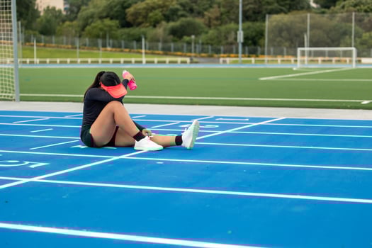 Exhausted Latina Runner Athlete Resting with Water Bottle on Athletic Track photo