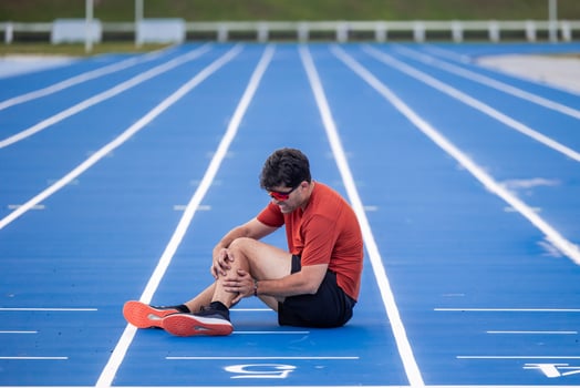 Injured Runner Clutches Leg in Pain on Athletic Track After Muscle Injury photo