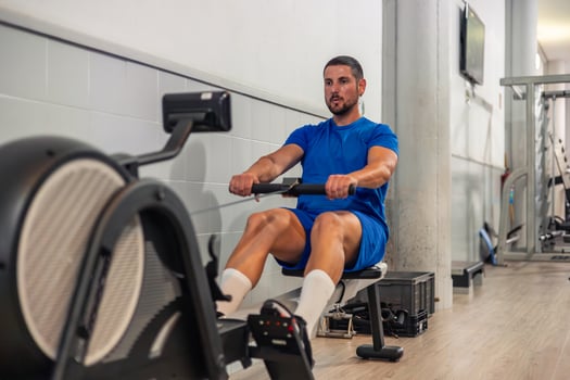 athlete trains cardio and resistance with rowing machine in gym photo