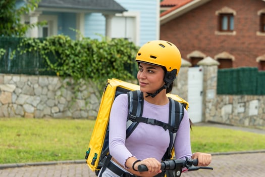 Closeup of Latina food delivery girl with yellow backpack and helmet on electric scooter photo