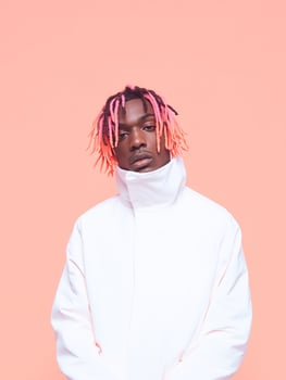 Young african male with pink dreadlocks on peach background. photo