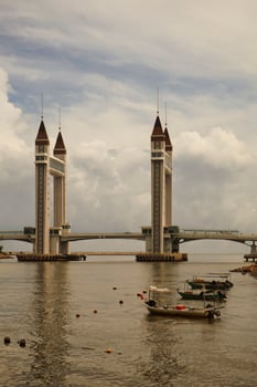 A stunning photogenic Kuala Terengganu drawbridge under a dramatic cloudy sky with structure featuring twin towers and a modern design that nestled against the ocean below. photo