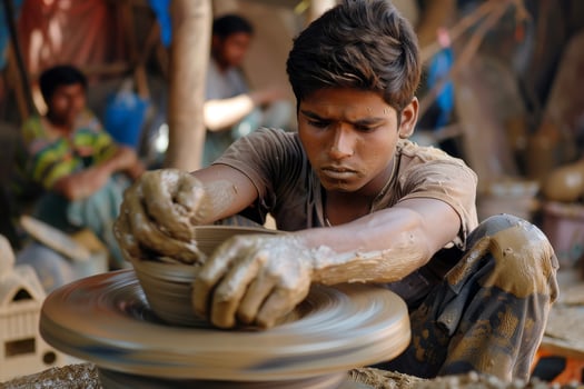 A young man is making a pot on a potter's wheel photo