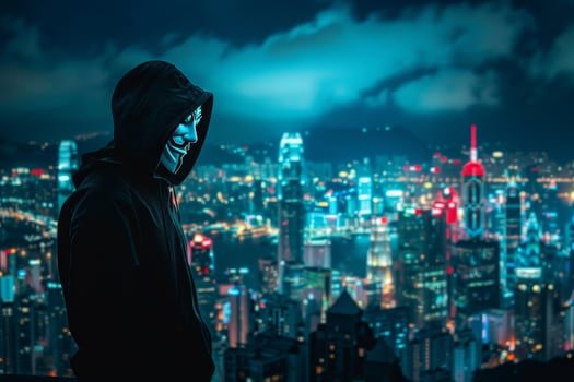 Anonymous hacker in black hoodie standing in front of cityscape at night photo