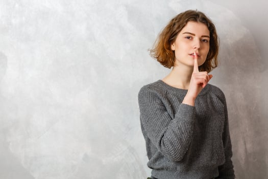 Portrait of young woman shows hush, shhh shush gesture, taboo, asks to keep quiet, gossiping, stands over white background photo
