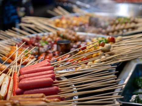 Stewed pot with meatballs and sausages skewers in hot spicy red sauce. Asian street food. photo
