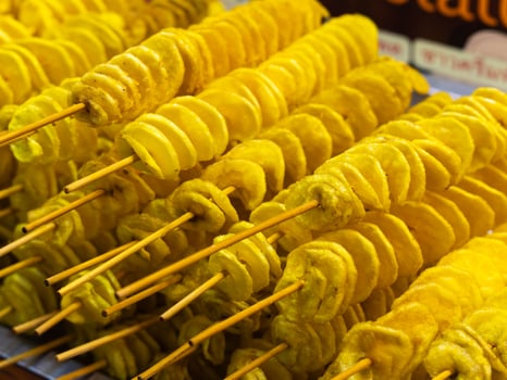 Spiral potatoes fried on a stick on a tray at a night market. Asian street food Thailand. photo